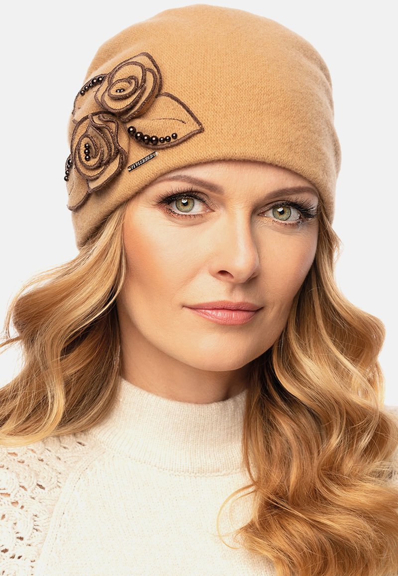 Gorro de punto color camel con apliques florales y acentos de cuentas en el lado. Textura suave, diseño ajustado y detalles de bordado simples.