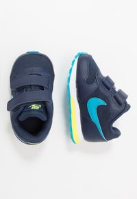 Marinblå barnsneakers med kardborreband, texturerad ovandel, ljusblå detaljer och vit sula med gula inslag.