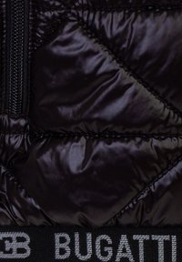 Giacca a vento nera in tessuto lucido, con cuciture diagonali e una zip nera. Logo "BUGATTI" in grigio sulla vita.