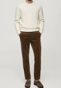Pull crème associé à un pantalon en velours côtelé marron et des mocassins marron, offrant une texture douce et une coupe décontractée.