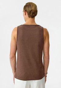 Bruine tanktop van zachte stof, met een eenvoudig ontwerp, een ronde hals en een ontspannen pasvorm, die de achterkant laat zien.