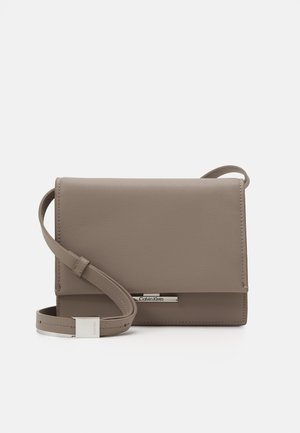 Borsa a tracolla Calvin Klein in materiale beige texturizzato. Forma rettangolare con chiusura a patta magnetica e accentuazione del logo in tono argento.
