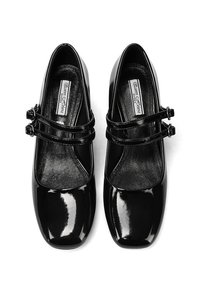 Scarpe in vernice nera con punta quadrata, dotate di due cinturini regolabili con fibbie. Finitura liscia con rivestimento interno morbido.