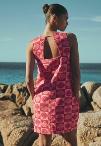 Ärmelloses Kleid aus rosa Stoff mit Muschelmotiv, mit einem Rückenausschnitt und Seitentaschen. Für eine lockere Passform entworfen.