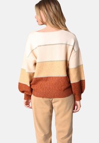 Pull surdimensionné multicolore avec des rayures en crème, beige et rouille, doté de poignets et d'un ourlet côtelés, confectionné en matériau texturé doux.