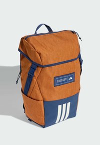 Orange stofrygsæk med marineblå accenter, justerbare stropper, forlommer og tre hvide striber nederst. Tekstureret finish.