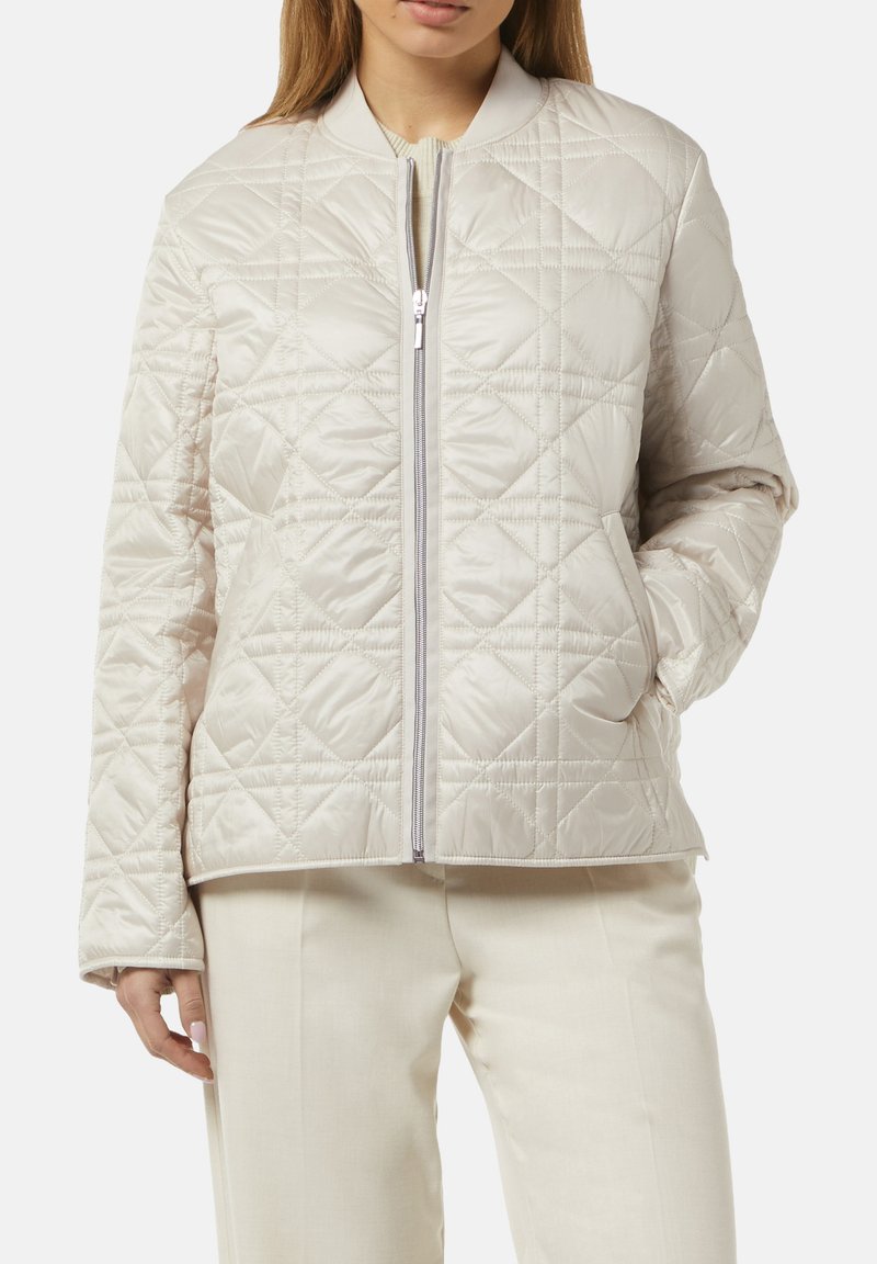 Beige gesteppte Jacke mit hohem Kragen, Frontreißverschluss und leichtem Finish. Mit Rautenmuster und Seitentaschen.