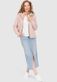 Felpa leggermente rosa con zip, camicia bianca con bottoni, gonna midi in denim blu con spacco laterale e sneakers bianche. Tessuti morbidi e vestibilità casual.