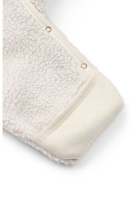 Měkká, krémově zbarvená fleecová látka s texturovaným povrchem. Má hladký manžet a zlaté patentky podél okraje pro zapínání.