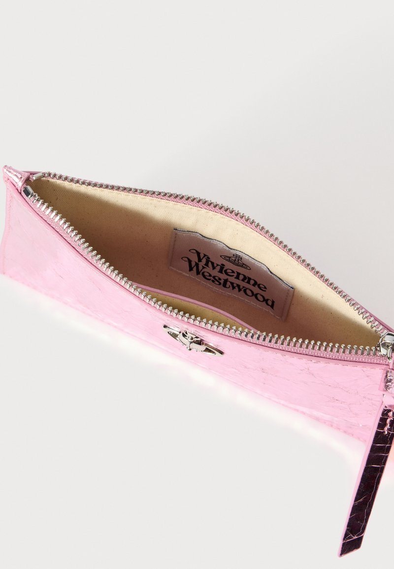 Cartera de charol rosa con cierre de cremallera, con acabado metálico, forro interior beige y etiqueta con el logo de Vivienne Westwood.