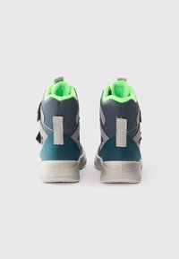 Baskets montantes bleu et gris avec une doublure intérieure vert fluo. Les caractéristiques incluent des sangles Velcro et une semelle en caoutchouc texturée.