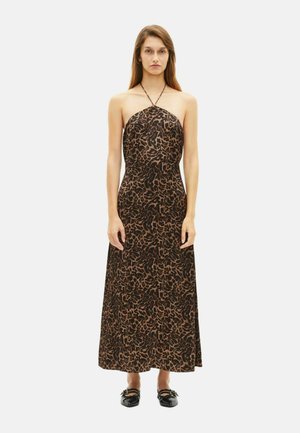 Robe maxi à imprimé animal noir et marron. Présente un design à encolure halter avec un corsage ajusté et un tissu fluide. Les chaussures sont des ballerines noires.