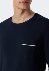 Marineblauwe katoenen t-shirt met een ronde halslijn en korte mouwen. Voorzien van een borstzak met een witte stripe-accent. Soepele textuur.