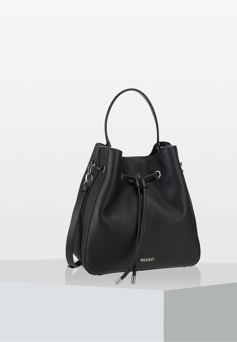 Sac seau en cuir noir avec une finition texturée, fermeture à cordon ajustable, poignée courte et bandoulière détachable. Logo à la base.