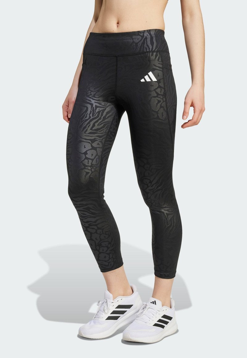 Leggings sportivi neri con un design a stampa animale testurizzato, elastico alto in vita e logo Adidas bianco sulla coscia sinistra.