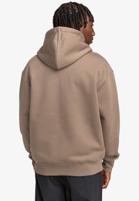 Hooded sweatshirt in light brown, made of soft material. Features a relaxed fit with ribbed cuffs and waistband. Simple, unadorned design.