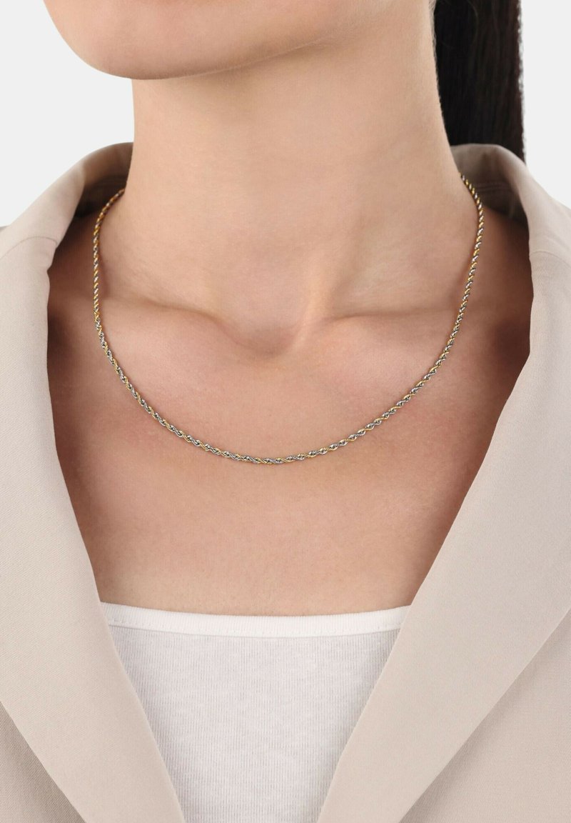 Guld- och silvervriden kedja halsband, slät textur, sitter tätt runt halsen, stylar med en ljusbeige kragjacka.