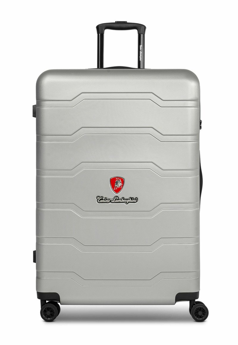 Maleta rígida plateada con una superficie texturizada, que presenta un diseño embosado, un mango telescópico y cuatro ruedas negras. Logotipos visibles.