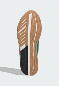 Podošva topánky s viacerými textúrami, vyrobená z gumy a syntetických materiálov, s farebnou schémou v zelenej, červenej a čiernej farbe.