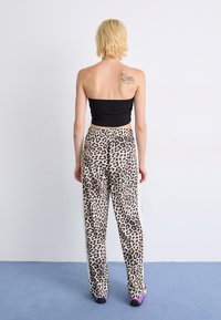 Leopard print wide-leg pants with an elastic waistband, accompanied by a black fitted top; soft fabric and detailed feline pattern.