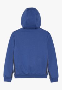 Modrá mikina s kapucí, která má jemnou texturu, žebrované manžety a boční pruhy. Jednoduchý design bez předních detailů, zaoblený výstřih.