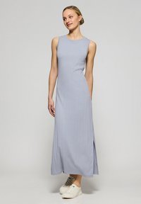 Lichtgrijze, mouwloze maxi-jurk met geribbelde textuur, zijsplitten en een ronde halslijn; gecombineerd met witte sneakers.