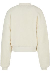 Valkoinen, pehmeä fleece-takki, jossa on lyhennetty muotoilu, ribbireunuksellinen kaulus ja hihansuut. Ominaisuudet include pehmeä, teksturoitu pinta ja roikkuvat olkapäät.