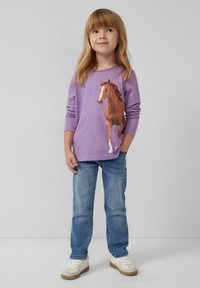 Paarse lange mouwen shirt met een bedrukt bruin paardenontwerp, gecombineerd met lichtblauwe jeans en witte sneakers met rubberen zolen.