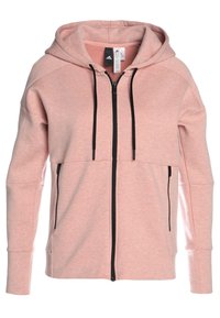 Sweat à capuche zip-up rose clair avec cordons noirs et poches latérales zippées, présentant une coupe décontractée et le logo Adidas sur l'étiquette intérieure du col.