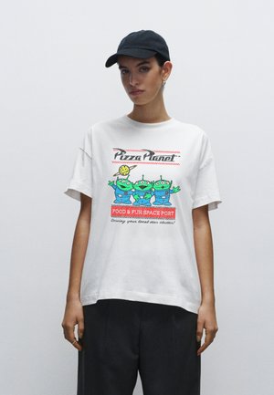 White t-shirt featuring colorful cartoon aliens and "Pizza Planet" text with red accents, relaxed fit, crew neck, short sleeves.