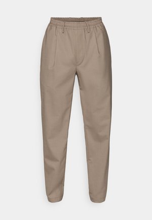 Beige, leichte Hose mit elastischem Bund, zwei vorderen Falten und schmal zulaufenden Beinen. Glatte Textur mit klaren Linien und ohne sichtbare Muster.