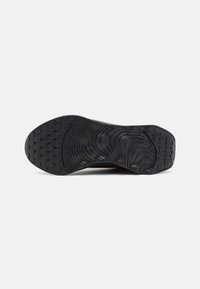 Semelle de chaussure en caoutchouc noir avec une surface texturée, présentant des motifs et des rainures variés pour l'adhérence et la flexibilité.