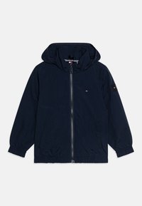 Marineblauwe lichtgewicht jas met een ritssluiting, kap, elastische manchetten en zijzakken. Voorzien van het Tommy Hilfiger-logo op de borst en de mouw.