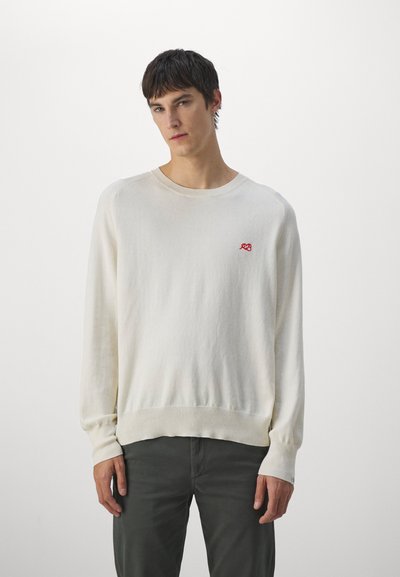 Pulover crem cu guler rotund, cu manșete și tiv din tricot. Prezintă un mic logo roșu brodat pe partea stângă a pieptului. Material moale, texturat.