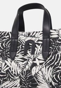 Černobílá vzorovaná taška na rameno se širokými listovými motivy, černými koženými držadly a výrazným embosovaným logem.