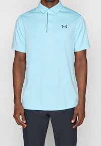 Jasnoniebieska koszulka polo z krótkim rękawem, teksturowany materiał, zapięcie na trzy guziki oraz małe czarne logo po lewej stronie klatki piersiowej.