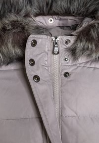 Ljust grå pufferjacka med huva i konstfuskpäls, med en central dragkedja och tryckknappar, slät tyg med en subtil lyster.