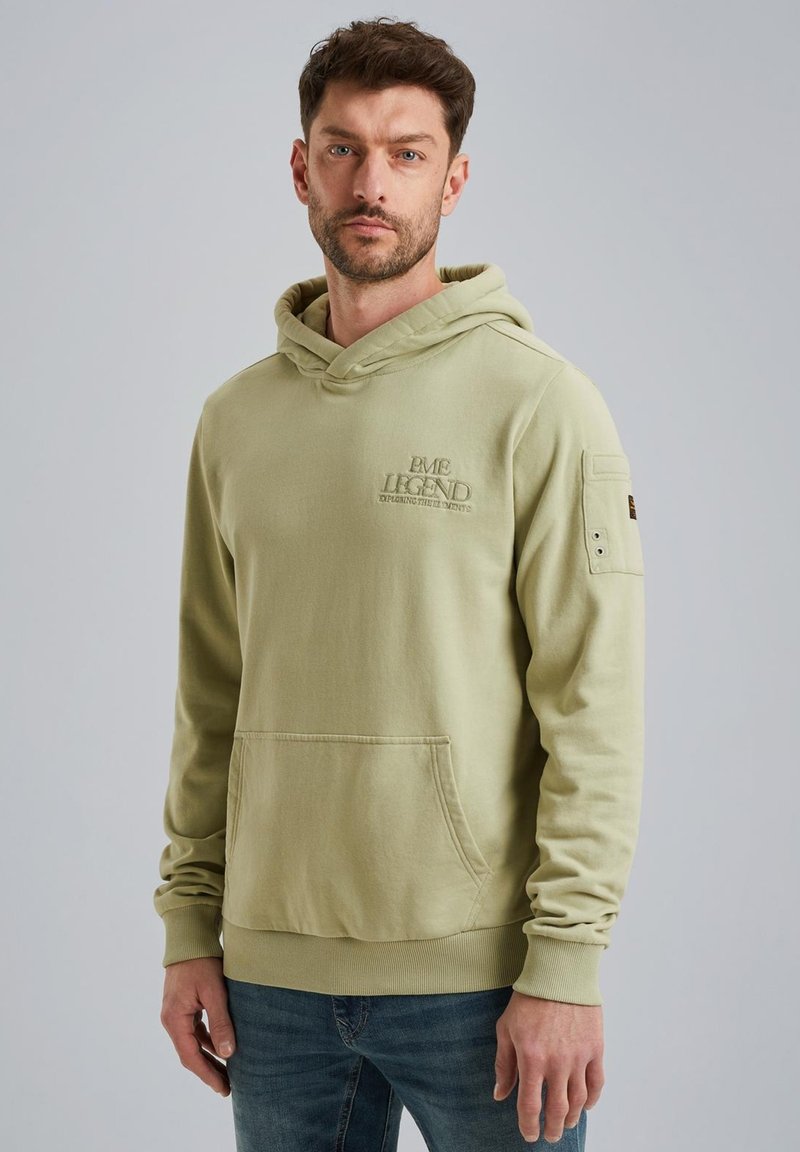 Felpa verde chiaro, materiale in cotone, vestibilità rilassata, tasca frontale, polsini e orlo a coste, logo ricamato sul petto, toppa discreta sulla spalla.