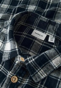 Marineblauw en witte geruite flanellen shirt met een zachte textuur, voorzien van een button-down kraag en een merklabel aan de binnenkant.