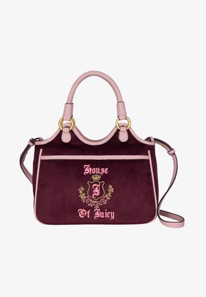 Paarse fluwelen tas met lichtroze leren accenten, gouden hardware, korte handvatten, verstelbare schouderband en geborduurd logo-detail aan de voorkant.