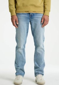Hellblaue Jeans aus Denim mit geradem Bein, getragen mit einem gelben Sweatshirt und weißen Sneakers. Der Stoff hat eine leicht ausgewaschene Textur.