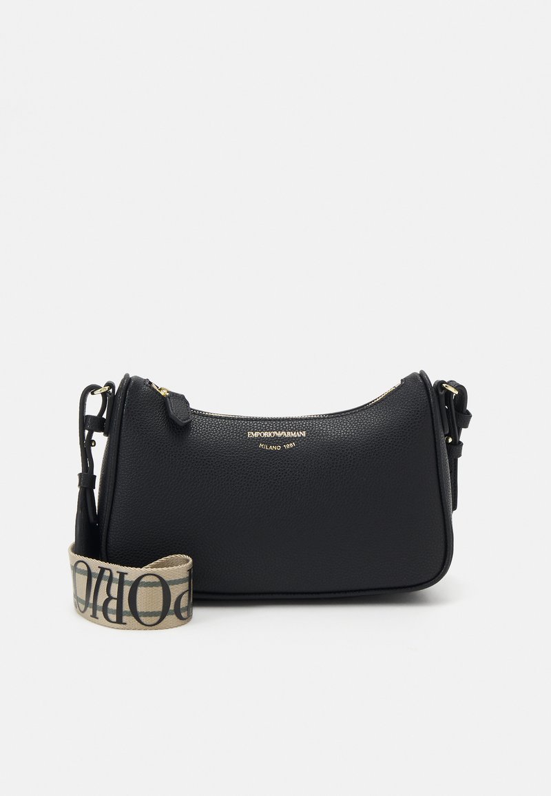 Črna usnjena torbica z teksturo, ukrivljene oblike, z zlatim okovjem in odstranljivim bež trakom z črnim napisom.