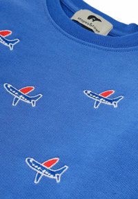 Niebieski sweter z haftowanymi wzorami samolotów w kolorach czerwonym i białym. Okrągły dekolt, miękka tekstura i luźny krój. Widoczna metka marki.