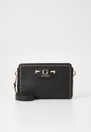 Borsa a tracolla in pelle nera con cuciture color crema, dotata di logo metallico, tracolla rimovibile e chiusura con zip. Forma rettangolare compatta.