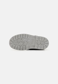 Suela de zapato de goma con un patrón de formas de flores y surcos, de color gris, con la marca 'superfit' y el número de talla 25 moldeado.