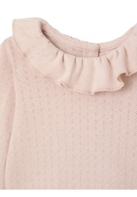 Helles rosa Oberteil mit einem rüschengestalteten Ausschnitt, aus strukturiertem Stoff mit kleinen Lochmustern gefertigt. Rückenschluss mit einem einzelnen Knopf.