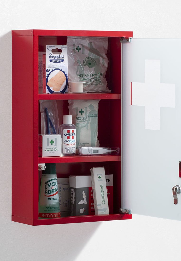 Roter Erste-Hilfe-Schrank mit offener Tür, der Verbände, ein Softeisbeutel, Desinfektionsmittel, chirurgisches Klebeband, Wattebäusche, ein Thermometer und medizinische Vorräte zeigt.