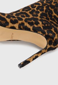 Luipaardprint stiletto hak met zwarte accenten. Getextureerd bont bovenwerk en een gladde beige zool met de merknaam "ALDO."