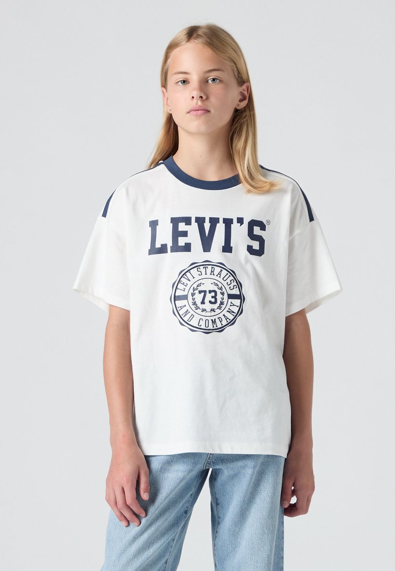Baltas īsām piedurknēm T-krekls ar tumši zilu apkakli un plecu akcentiem. Centrā ir liels "LEVI'S" logo un zīmoga dizains. Mīksta kokvilnas tekstūra.