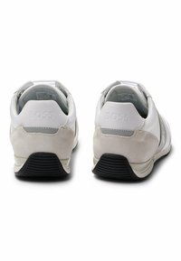 Sneaker bianche con una combinazione di texture liscia e scamosciata; presentano un accento grigio e una suola in gomma nera. Il marchio è visibile sul tallone.